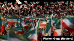 Njerëz duke valëvitur flamuj në një ngjarje në kampin Ashraf-3, ku janë të strehuar pjesëtarët e opozitës iraniane në Shqipëri. Manzë, 13 korrik 2019.