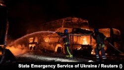 Tűzoltók birkóznak a lángokkal egy, az orosz légicsapásokban megrongált parkolóban Kijevben 2023. május 16-án