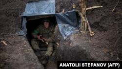 Український піхотинець 57-ї окремої мотопіхотної бригади сидить в окопі на сході України 