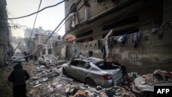 Disa persona shihen pranë ndërtesave të goditura nga sulmet ajrore izraelite në Rafah, në jug të Rripit të Gazës më 9 shkurt 2024. 