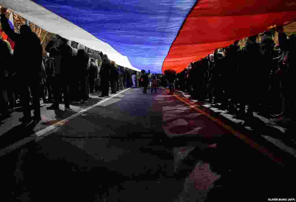 Protestatari țin un steag sârb uriaș în timpul unui miting la Belgrad împotriva autorităților sârbe și a unui plan franco-german pentru rezolvarea problemei Kosovo.