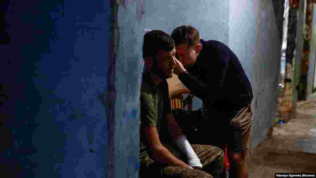 Egy katonaorvos vizsgál egy sérült ukrán katonát a Harkivi területen, a frontvonal közelében felállított ideiglenes egészségügyi bázison&nbsp;június 2-án. A súlyosabb sebesülések ellátását már a páncélozott mentőautóban, menet közben megkezdik