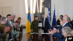 Zvaničnici aplaudiraju ukrajinskom predsjedniku Volodimiru Zelenskom (lijevo) i grčkom premijeru Kyriakosu Micotakisu nakon potpisivanja sporazuma u Atini, 21. avgusta 2023. Zelenski je bio u Grčkoj na razgovorima s rukovodstvom zemlje i prisustvovao neformalnom sastanku balkanskih lidera sa najvišim zvaničnicima EU.