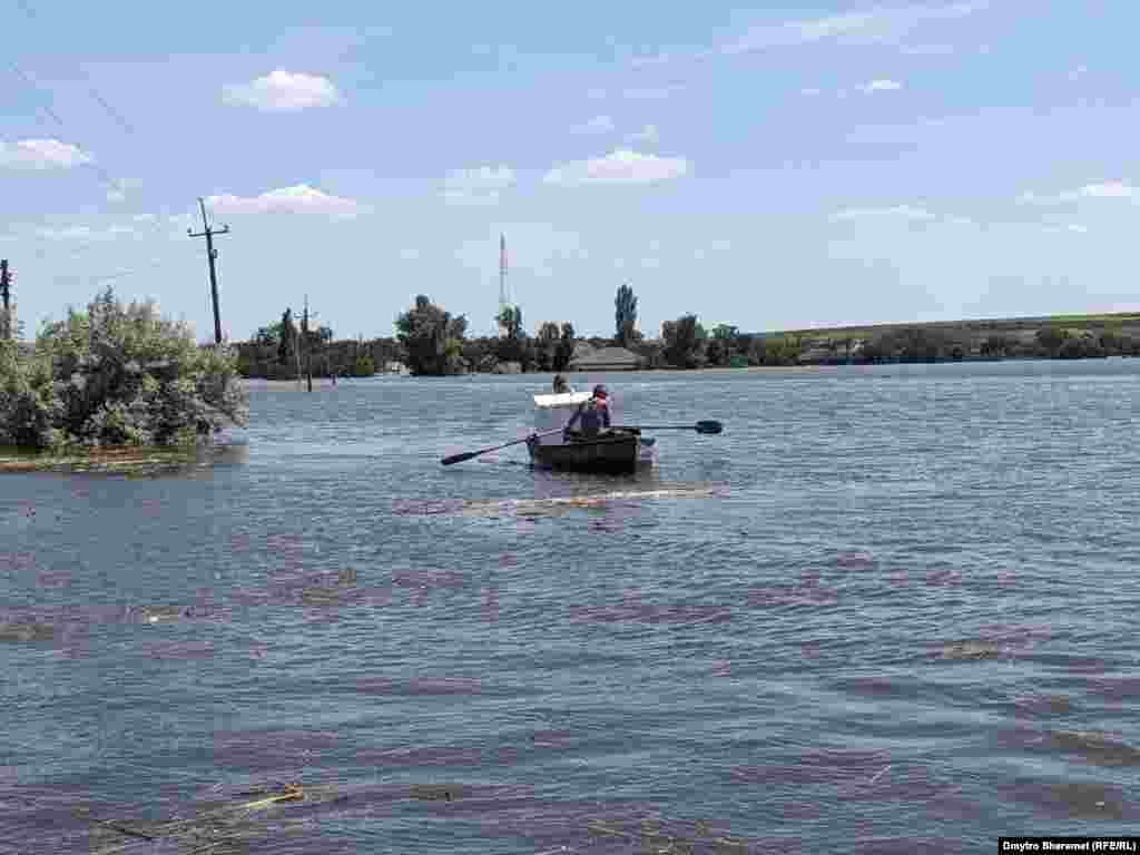 Oamenii își salvează bunurile cu ajutorul bărcilor.