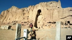 Afganistanski dječak pumpa vodu u blizini arheološkog nalazišta 55 metara visoke statue Bude u Bamijanu, centralni Afganistan, 18. decembra 1997. 
