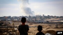 Dy djem duke e shikuar tymin që ngrihet lart nga ndërtesat në Rafah, Gazë, gjatë sulmeve izraelite kundër Hamasit, 31 maj 2024.