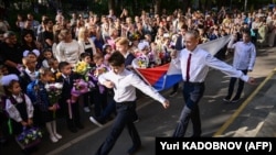 Школьники маршируют с российским флагом во время церемонии «первого звонка» по случаю начала учебного года в Москве, 1 сентября 2023 года