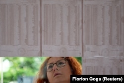 Një qytetare në Tiranë duke shikuar listat e votuesve të vendosura para një qendre të votimit në Tiranë.