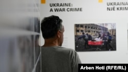 یک بازدیدکننده از نمایشگاه به عکس ایرینا کالینینای ۳۲ ساله نگاه می‌کند که با برانکارد از زایشگاه بیرون برده می‌شود. کالینینا و نوزادش از حمله موشکی روسیه در مارس ۲۰۲۲ جان سالم به در نبردند. عکس از اوگنی کالولکا از خبرگزاری آسوشیتدپرس که برنده عکس سال مطبوعات جهان شد.