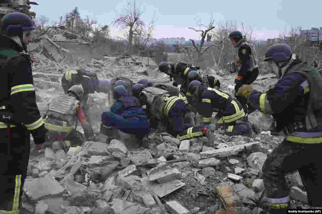 Рятувальники намагаються знайти людей під завалами зруйнованих російськими ракетами будинків Запоріжжя. 22 березня 2024 року. Станом на ранок було відомо про одного загиблого. Ще восьмеро людей зазнали поранення, двоє вважаються зниклими. Ці дані не є остаточними. Рятувальні роботи і пошук людей триває