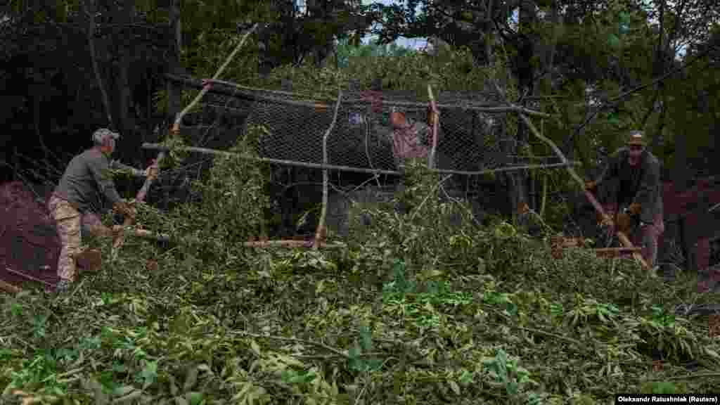 Sunt folosite ramurile de copac pentru a ascunde obuzierul de dronele inamice.