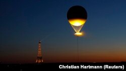 Flacăra olimpică în timp ce zboară deasupra Parisului, atașată de un balon.