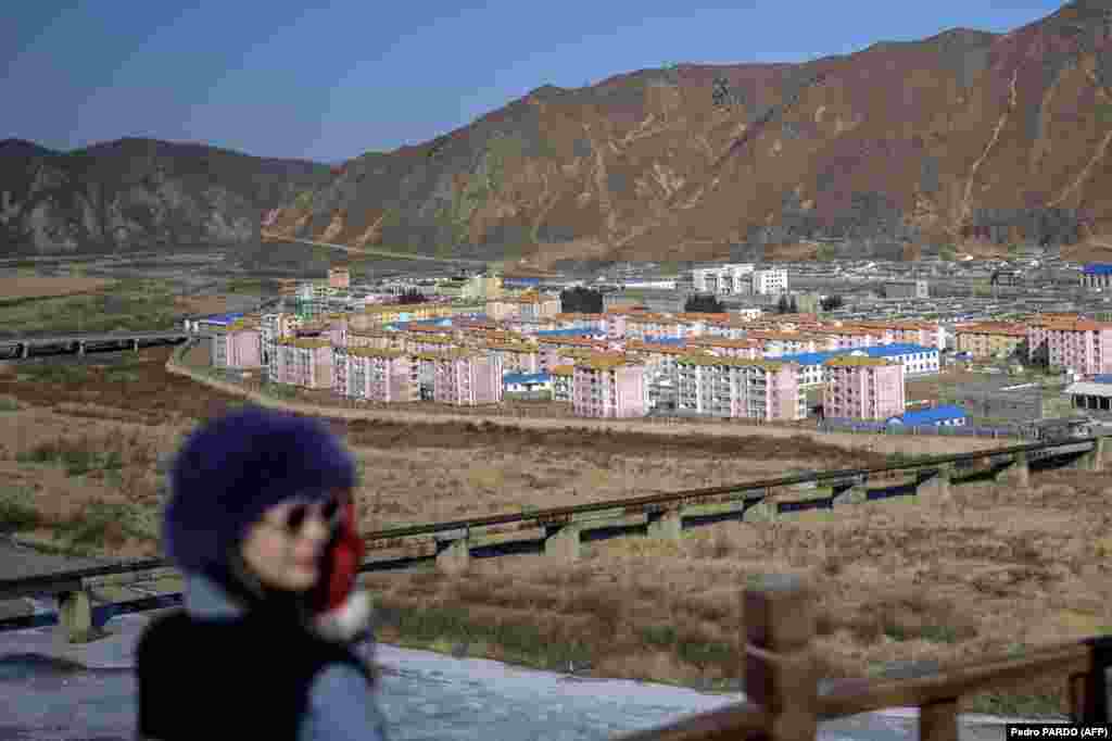 Ova fotografija snimljena 26. februara 2024. prikazuje ženu koja pozira na turističkom vidikovcu, sa sjevernokorejskim gradom Namyang u pozadini, pored rijeke Tumen u gradu Tumen u kineskoj sjeveroistočnoj provinciji Jilin.