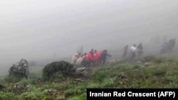 Ova fotografija preuzeta iz video snimka koji je objavio iranski Crveni polumjesec 20. maja 2024. prikazuje spasioce koji izvlače tijela na mjestu pada helikoptera predsjednika Ebrahima Raisija u maglom prekrivenom planinskom području sjeverozapadnog Irana. 
