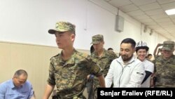 Азамат Ишенбеков менен Актилек Капаров Ленин райондук сотуна алынып келаткан учур. 7-июнь, 2024-жыл. 