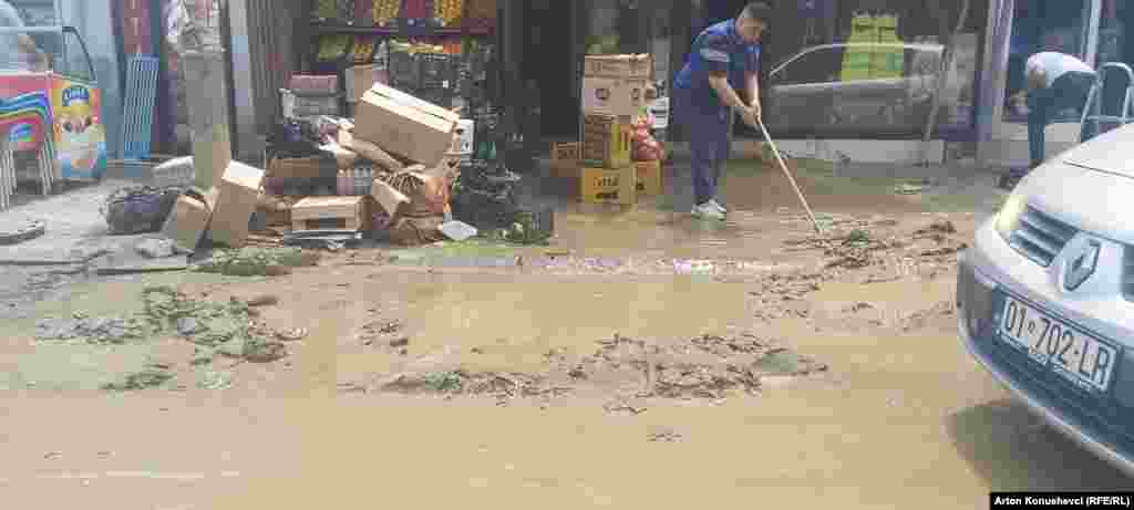 Radnik čisti ulicu ispred prodavnice