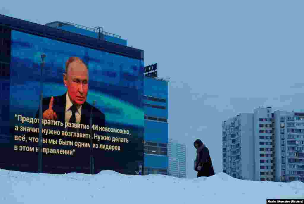 Žena prolazi pored ekrana na fasadi zgrade na kojoj se zavrtila slika ruskog predsjednika Vladimira Putina i citat sa njegove pres-konferencije na kraju godine, Moskva, Rusija.