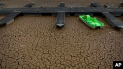 Zelena pedalina privezana za mol u osušenom dijelu akumulacionog jezera Sau