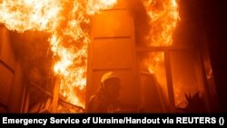 Një zjarrfikës duke tentuar të shuajë zjarrin në një ndërtesë administrative të dëmtuar rëndë nga një sulm raketor rus, Ukrainë, 20 korrik 2023.