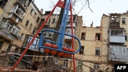 Празна детска люлка пред сграда, засегната от обстрел, в Харков. Снимката е от 30 януари