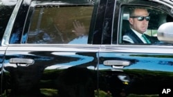 Дональд Трамп машет рукой на заднем сиденье автомобиля