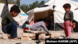 Afgán gyerekek játszanak a földrengés után felállított sátraknál Herát külvárosában 2023. október 18-án