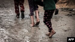 Palestinska djeca hodaju blatnjavom stazom u improviziranom kampu za raseljene Palestince, u Rafahu u južnom Pojasu Gaze, usred sukoba između Izraela i militantne grupe Hamas, 2. januara 2024.