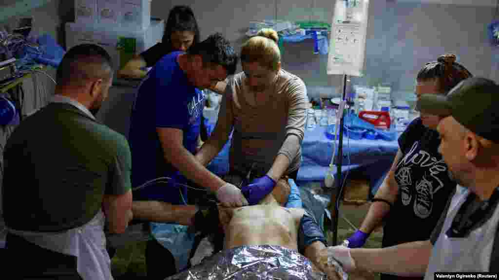 Sérült ukrán katona ellátása a frontvonal közelében, a Harkivi területen 2024. június 2-án. A sebesülteket először egy átmeneti állomásra szállítják, ahol stabilizálják az állapotukat. Szükség esetén innen viszik tovább őket, távolabbi kórházakba