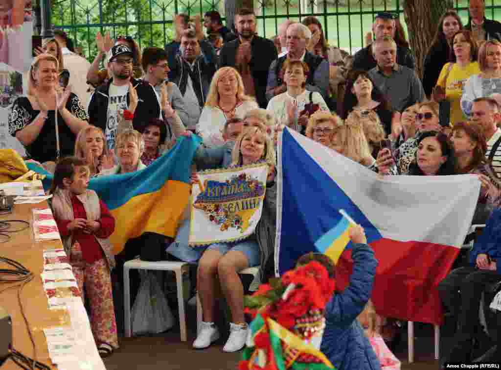 Українці на фото тримають в руках чеські та українські прапори. У Чехії проживає найбільша в ЄС кількість українських біженців з розрахунку на душу населення. Близько 339 000 українців наразі мають візи &laquo;тимчасового захисту&raquo;, які дають їм можливість жити та працювати в країні