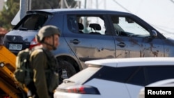 Ичиндеги үч палестиналык өлтүрүлгөн машиненин жанында турган израил аскери. 25-июль, 2023-жыл. 