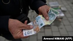Ulični prodavac pokazuje novčanice srpskih dinara u gradu Gračanici, centralno Kosovo, 1. marta 2024.