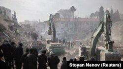 Люди наблюдают, как продолжаются поиски выживших после смертоносного землетрясения в Кахраманмараше, Турция, 10 февраля 2023 года.