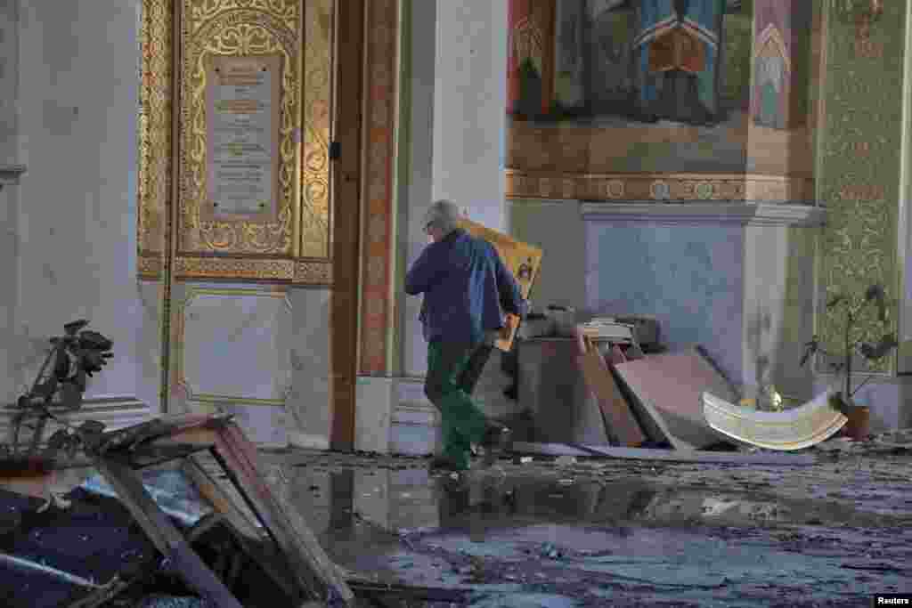 Un bărbat duce o icoană în interiorul Catedralei Schimbarea la Față, deteriorată în timpul unui atac cu rachete rusești, pe fondul atacului Rusiei asupra Ucrainei, la Odesa, Ucraina, 23 iulie 2023&nbsp;