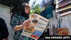 Жительница Тегерана читает газету с новостями о гибели президента