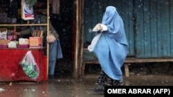 An Afghan woman in a burqa walks along a street.