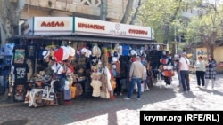 Люди у сувенирной лавки в центре Феодосии накануне начала курортного сезона, 15 апреля 2024 года