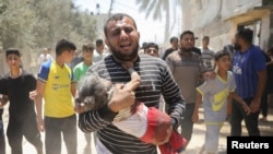 Жарадар болгон кызын көтөрүп бараткан палестиналык киши. Дейр ал-Балах, Газа тилкеси, 14-июнь 2024-жыл 