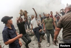 Palestinac (lijevo) drži tijelo djeteta nastradalog u izraelskom napadu u izbjegličkom kampu Džabalija, sjeverno područje Pojasa Gaze, 9. oktobra