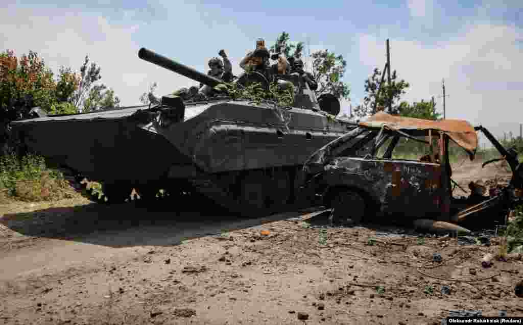 Українські військові на бойовій машині піхоти БМП-1 проїжджають повз знищений автомобіль.&nbsp;Нескучне, Донецька область, 13 червня 2023 року