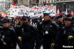 Policija hoda ispred demonstranata koji protestuju zbog penzione reforme u Francuskoj, Pariz, 14. april 2023.