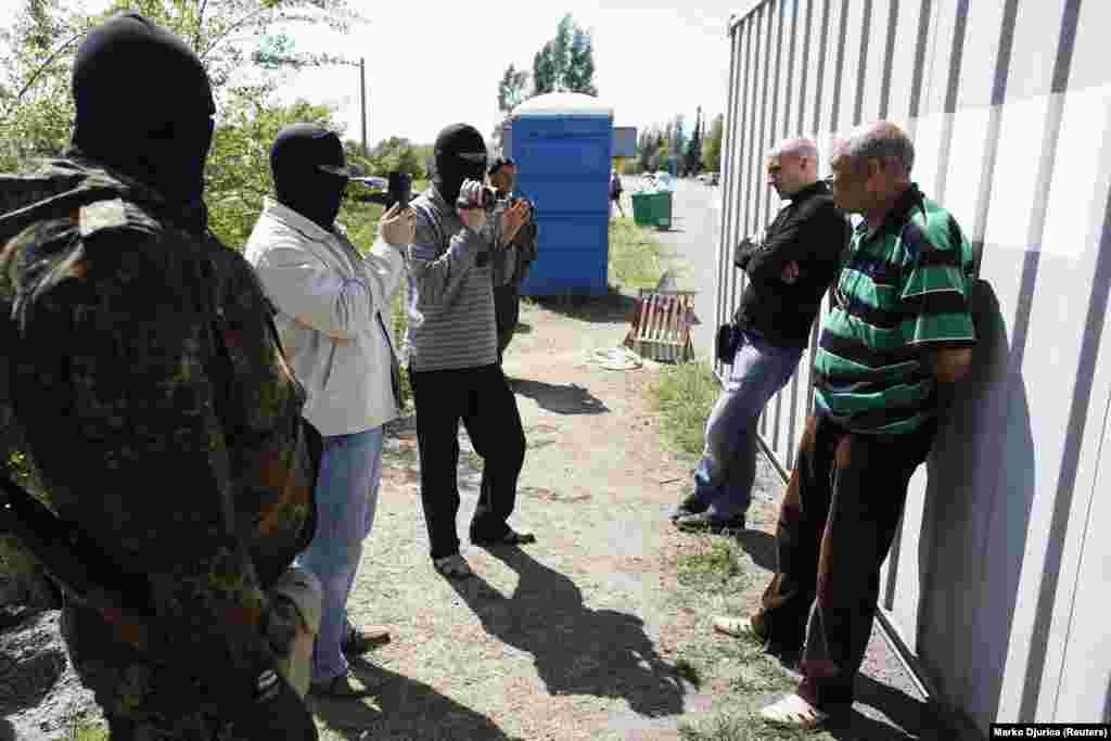 Poliția ucraineană interoghează doi bărbați la un punct de control din afara Mariupolului, la 11 mai 2014. Forțele ucrainene au înființat puncte de control în jurul Mariupolului, în timp ce situația din centru a rămas tensionată.