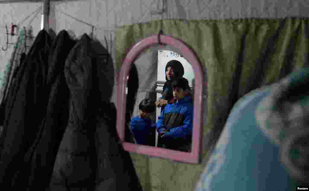 Reflektimi në një pasqyrë i Hatixhe Kindevit dhe djemve të saj, në tendën e tyre gjatë një dite me shi, janar 2024.