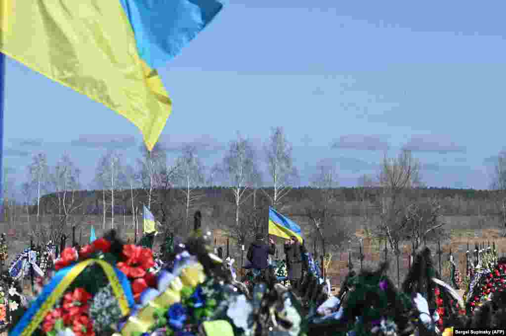 Familjarët pinë në kujtim të ushtarëve të rënë në Borodianka, afër Kievit, në mars 2023.