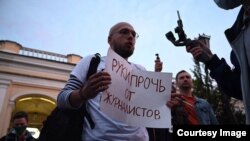 Арсений Веснин държи табела с надпис "Долу ръцете от журналистите" на протест в Санкт Петербург преди да напусне Русия