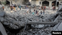 Palestinezë duke shikuar një vend të bombarduar nga Izraeli, në Han Junis, në jugun e Rripit të Gazës, më 23 tetor.