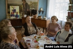 Місцеві мешканці співаюьь за столом і піднімають тости не за мир, а за перемогу