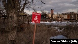 Un semn pe care scrie „Mine” este amplasat pe marginea drumului din satul Kamianka, la periferia orașului Izium, Ucraina, duminică, 19 februarie 2023. Fotografie de arhivă