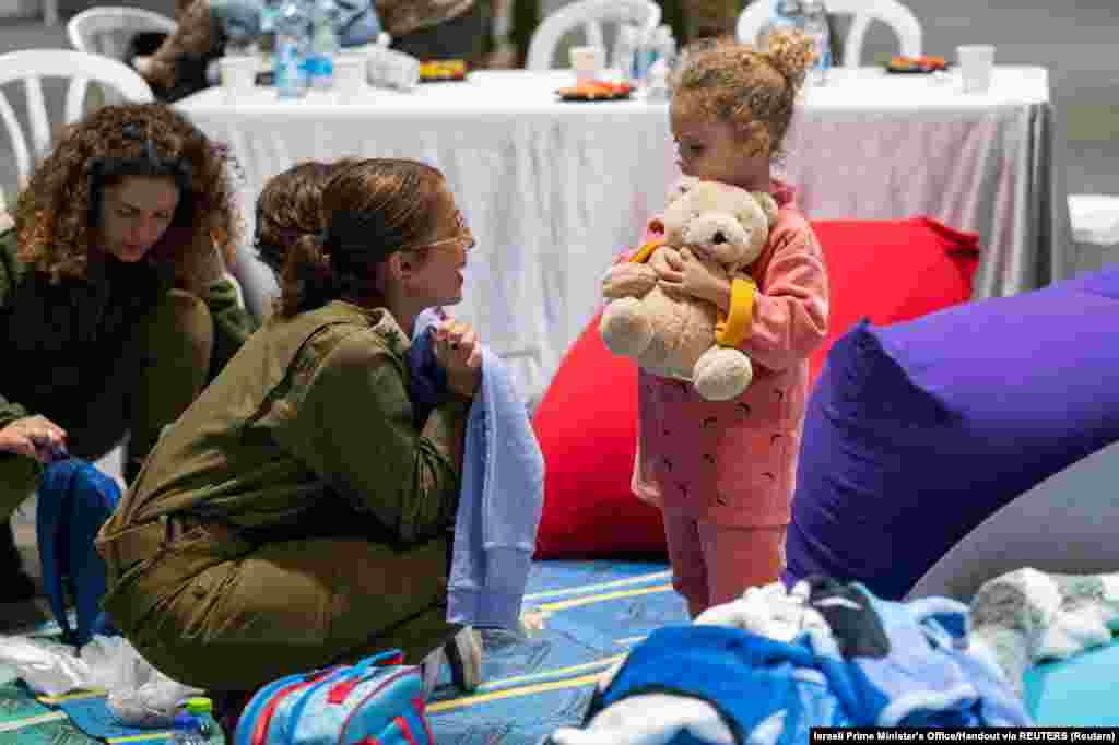 A hároméves, szabadon engedett izraeli túsz, Jahel Soham egy plüssállatot tart a kezében, miközben egy izraeli katonával beszélget nem sokkal azután, hogy november 25-én megérkezett Izraelbe