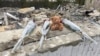 Flowers and a teddy bear are left at the site of the deadly strike in Hroza in Ukraine's Kharkiv region, which killed at least 51 people, including a child.