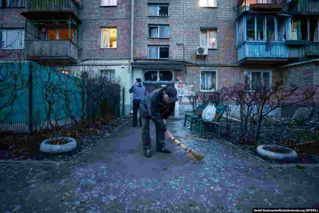 Чоловік замітає скло від вибитих ударною хвилею вікон